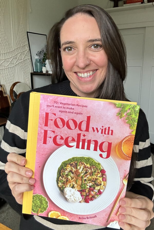brita britnell holding the Food with Feeling Cookbook