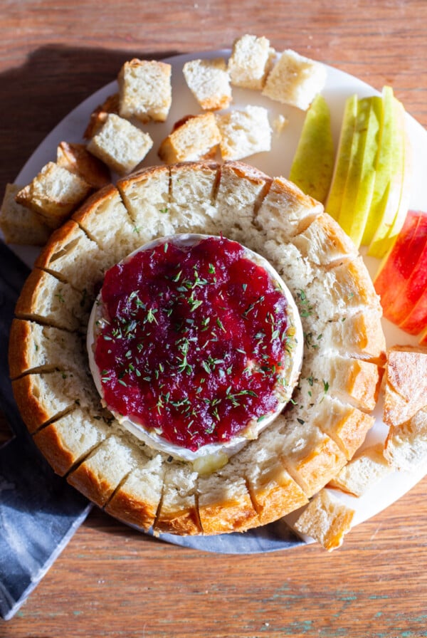 baked brie topped with cranberry sauce inside of a round loaf of bread