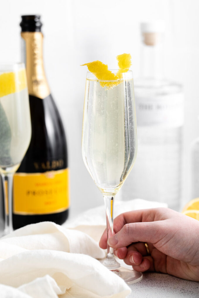 hand holding a French 75 Cocktail in a champagne flute