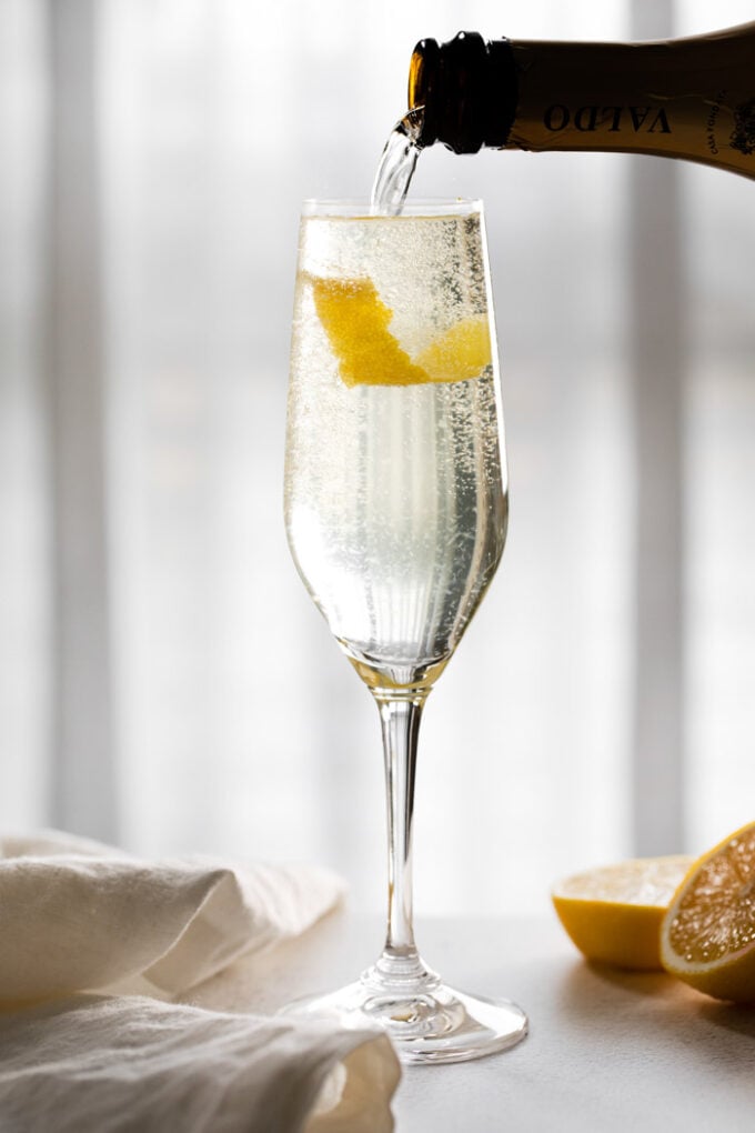 pouring champagne into a glass with a lemon twist