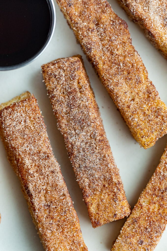 French toast sticks on a white plate with maple syrup.