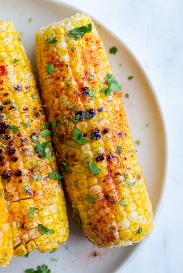 grilled corn stacked on a plate and brushed with sweet chili lime sauce + lime zest