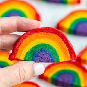 hand holding up a rainbow sugar cookie with more cookies in the background