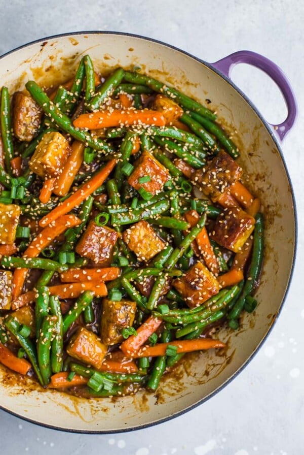 tempeh stir fry with green beans and carrots in a large skillet. topped with sesame seeds