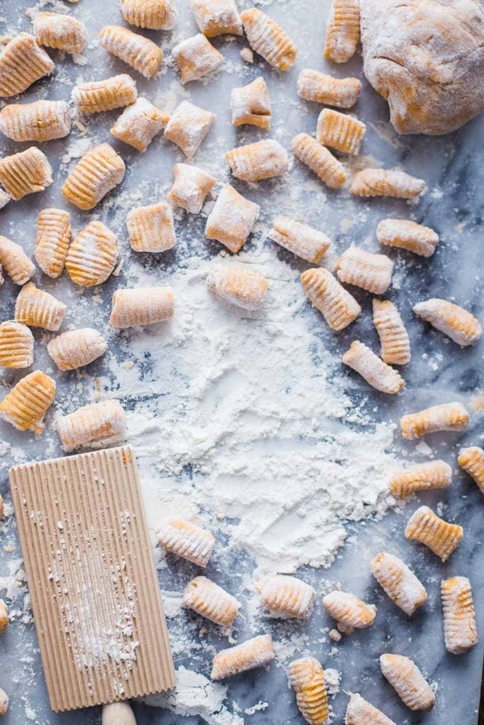 sweet potato gnocchi on a marble board with flour al around